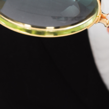 photo of two hands: one holding a pen, the other holding a magnifying glass