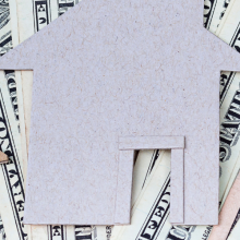 dollar bills overlain by cutouts of house shapes