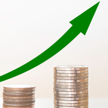 upward growth line over stacks of coins ending in a wooden house