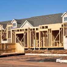 new homes under construction with machinery and road curb
