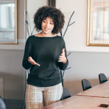 woman presenting in conference room to three people
