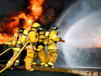 four firefighters spraying water on a fire