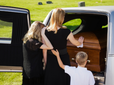 photo of family members near a casket and hearse