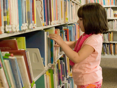 young child selecting library books
