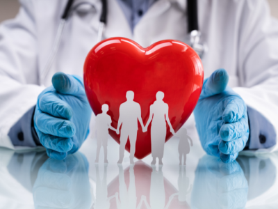doctor with blue gloved hands around cartoon heart and paper family. 
