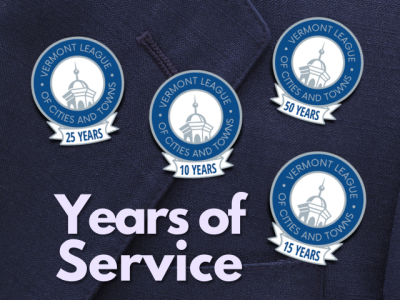 a dark lapel with special pins showing 10, 15, 25, and 50 years of service