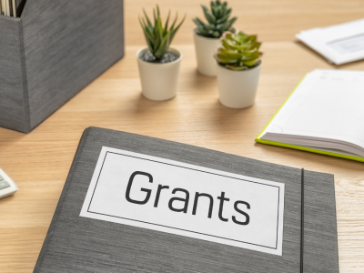 desk surface with papers and a folder labeled "Grants"