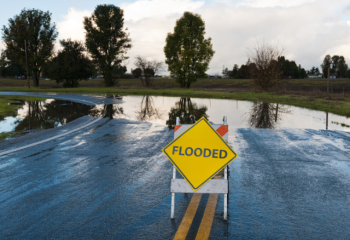 water across road with "FLOODED" sign in front