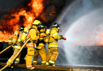four firefighters spraying water on a fire