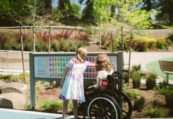 child pointing at sign alongside a woman using a wheelchair