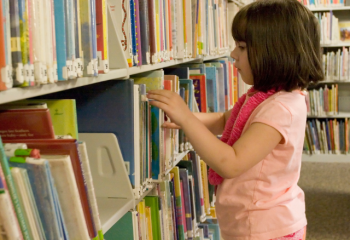 young child selecting library books
