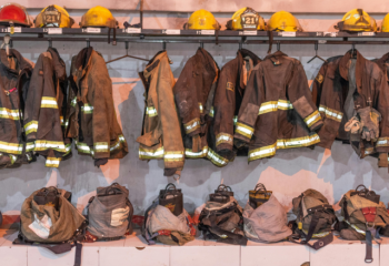 a row of firefighting gear - helmets, coats, and boots