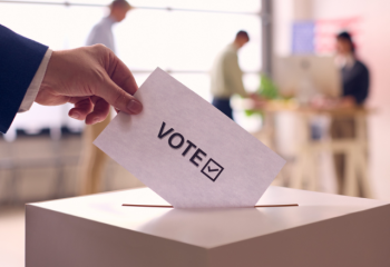 hand placing ballot into ballot box