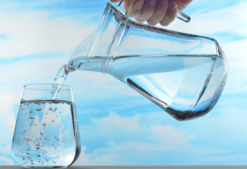 water being poured from a glass pitcher into a drinking glass