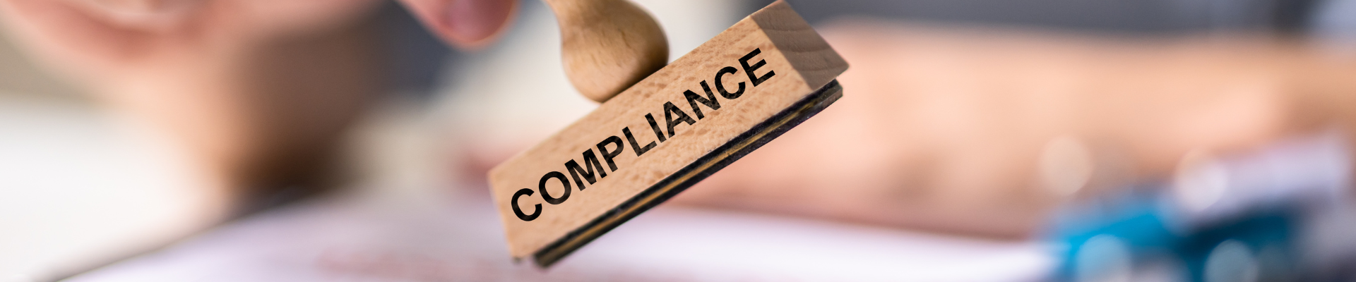a hand holding a stamp that reads "compliance"