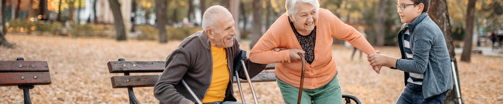 boy helping older adult with a cane rise from a bench