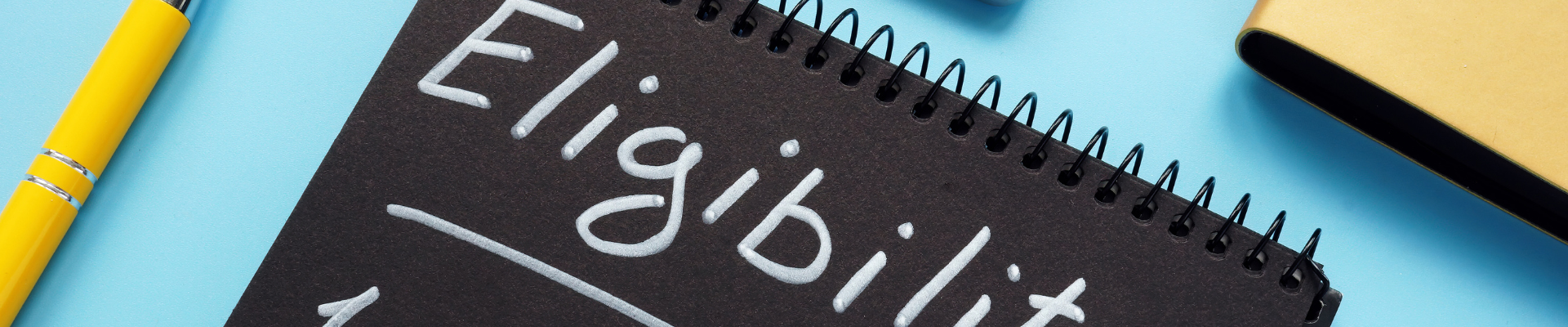 pen and notebook with "eligibility" on the notebook