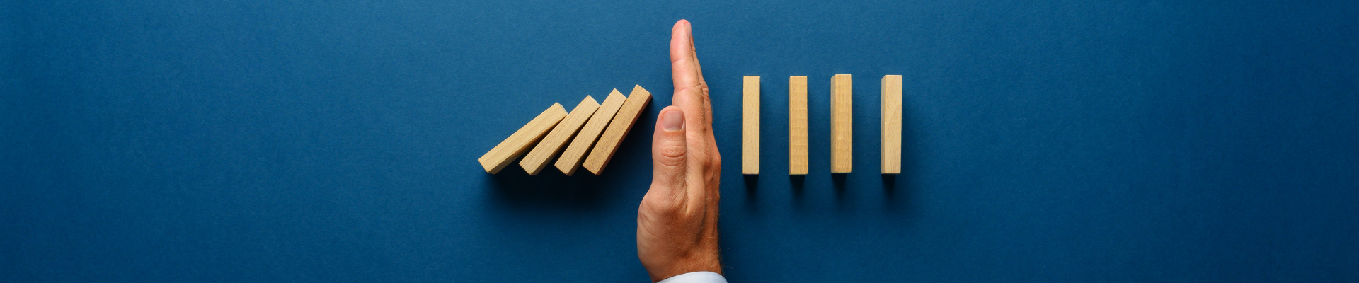 businessman's hand stopping falling dominoes
