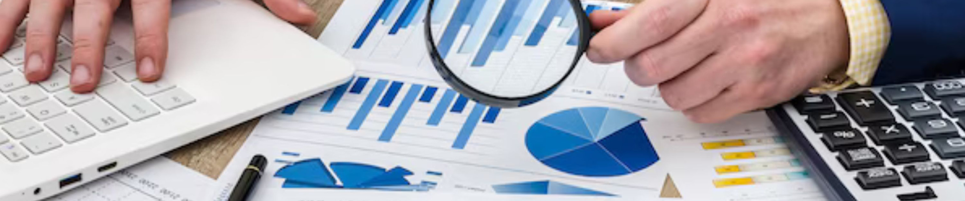 hand with magnifying glass examining financial report