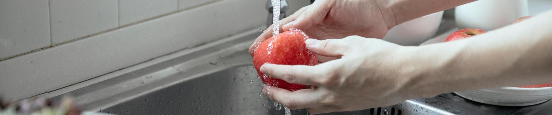 hands washing an apple at sink