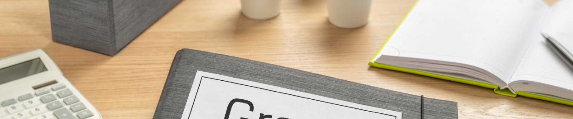 desk surface with papers and a folder labeled "Grants"