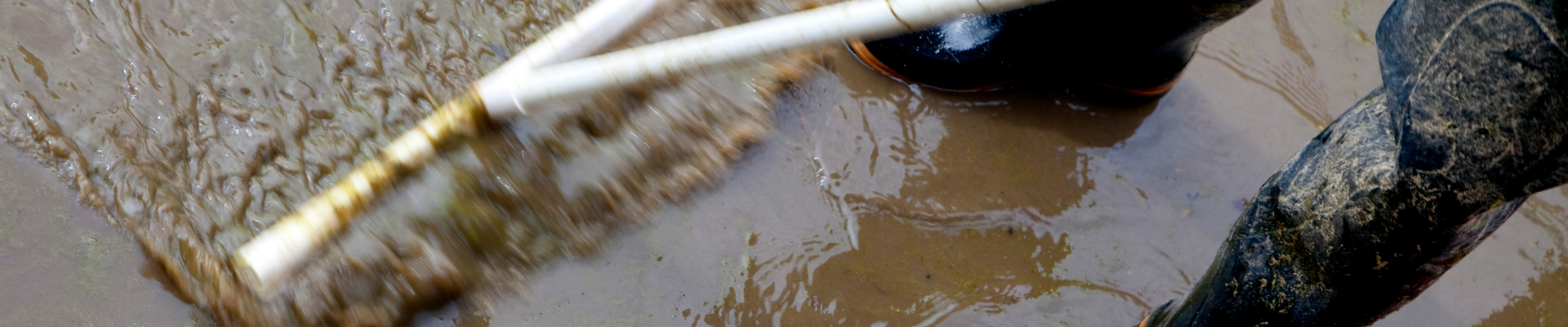 photo of unseen person in waterpfoof boots using squeegee to move flood water