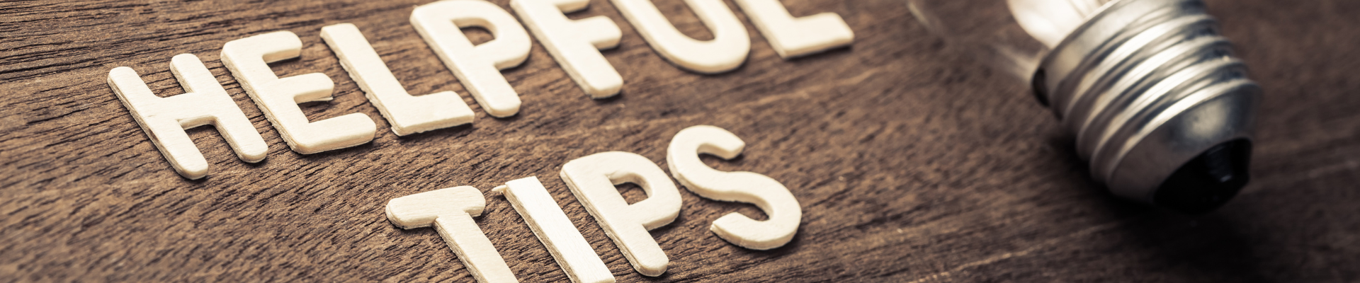 white letters spelling "helpful tips" on wood background with lightbulb