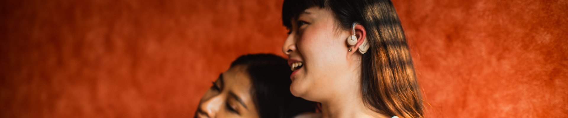 heads of two women, one is wearing a hearing aid