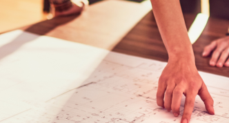 a table with a map and hands pointing to the map