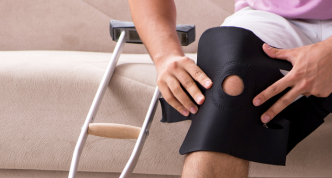 photo of person on couch with knee brace and crutch