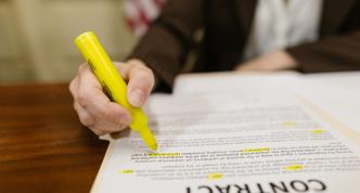 contract on table with person holding highlighter