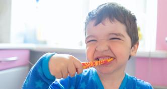 photo of smiling child brushing teeth