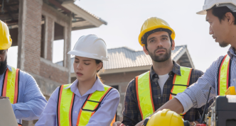four people collaborating on a housing project at a construction site