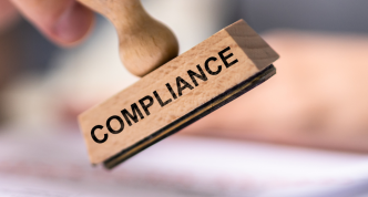 a hand holding a stamp that reads "compliance"