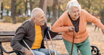 boy helping older adult with a cane rise from a bench