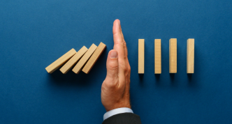 businessman's hand stopping falling dominoes