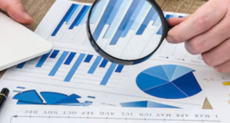 hand with magnifying glass examining financial report