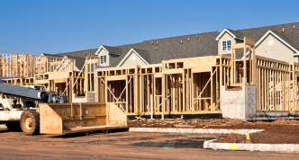 new homes under construction with machinery and road curb