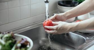 hands washing an apple at sink