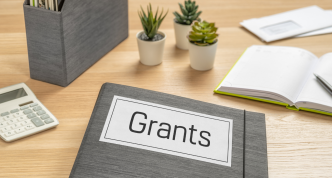 desk surface with papers and a folder labeled "Grants"