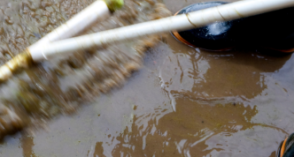 photo of unseen person in waterpfoof boots using squeegee to move flood water